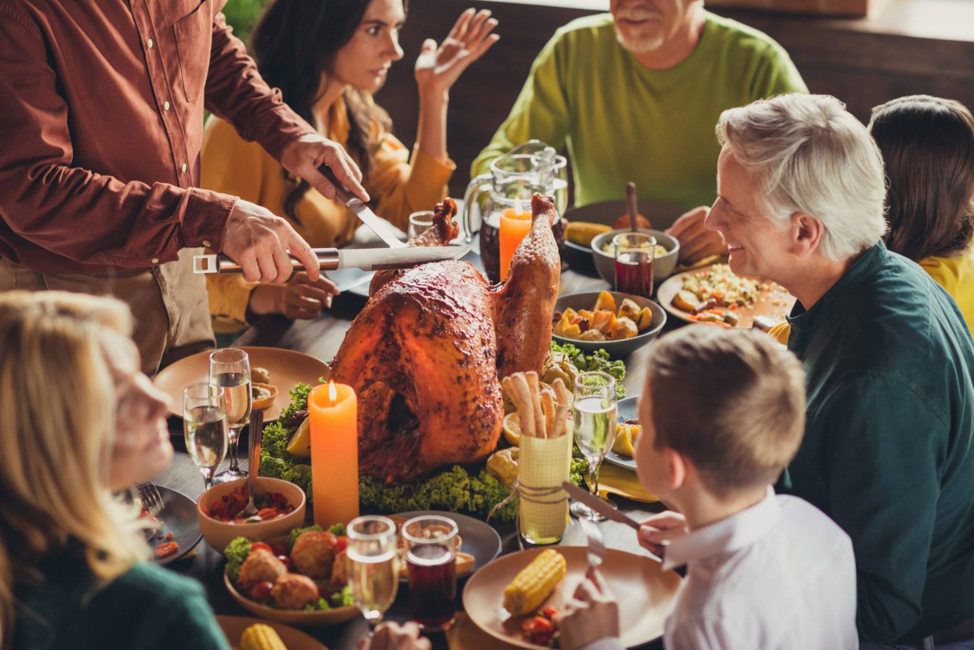 Cropped photo of family meeting served table thanks giving dinner two knives slicing stuffed turkey meal living room indoors Cropped photo of family meeting served table thanks giving dinner two knives slicing stuffed turkey meal living room indoors