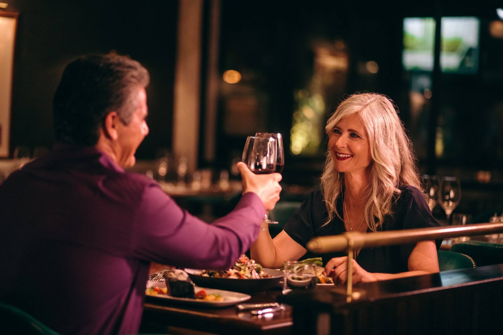 Smiling mature husband and wife toasting with wine at dinner Smiling mature husband and wife toasting with wine at dinner