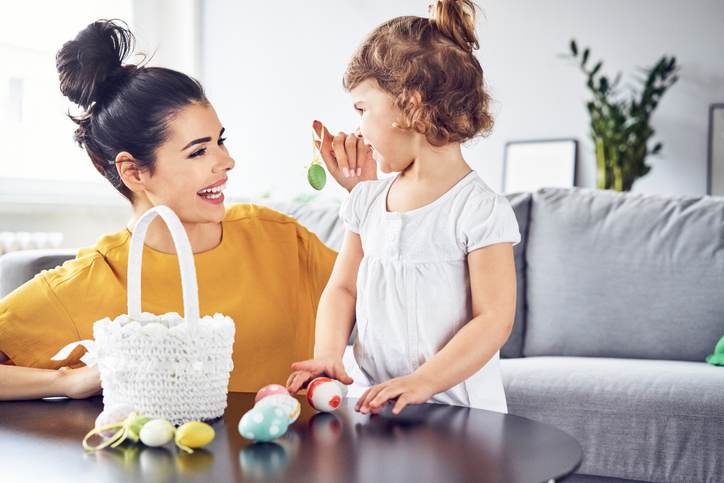 Happy mother playing with her child with Easter eggs