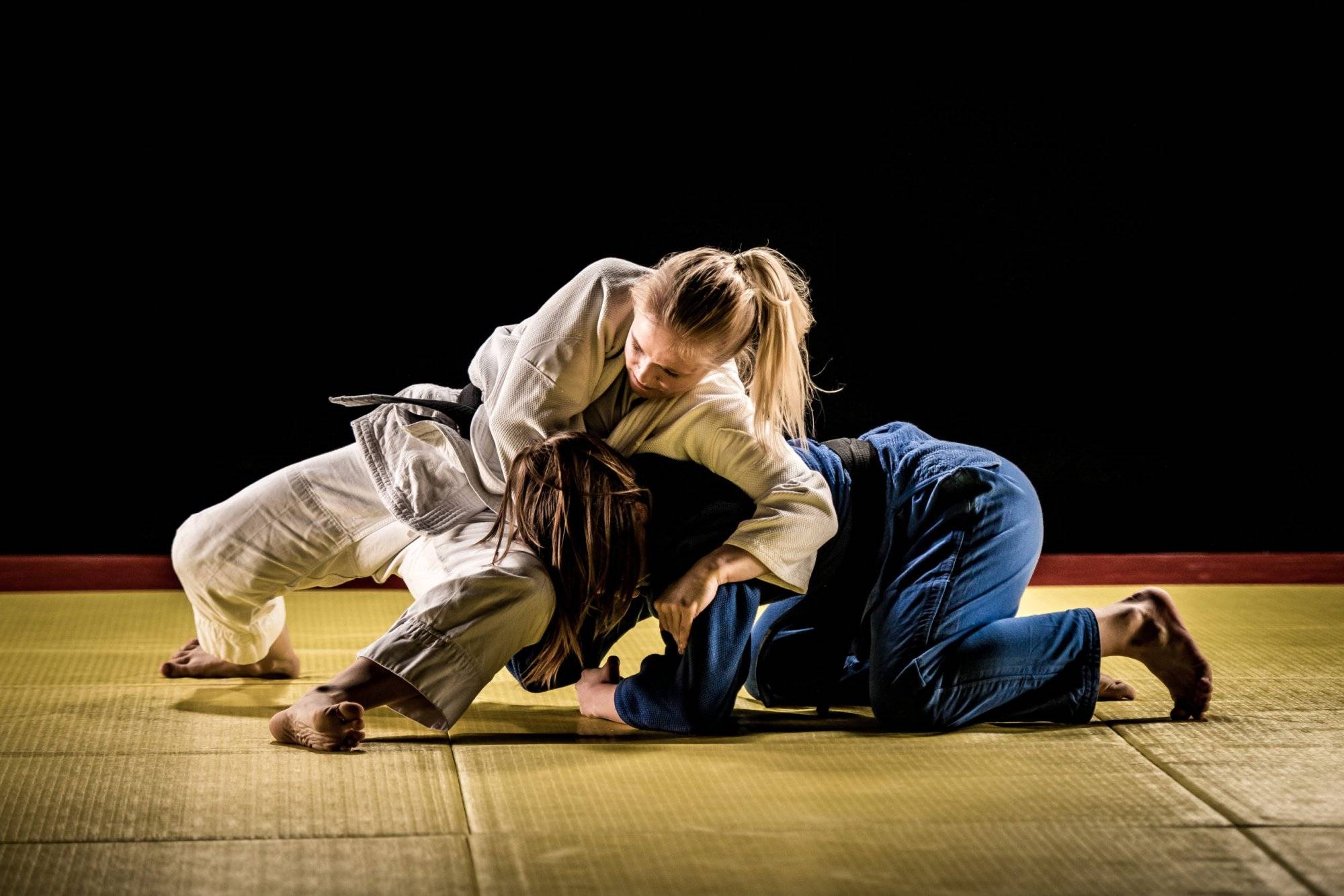 Two female judokas wrestling on a tatami mat