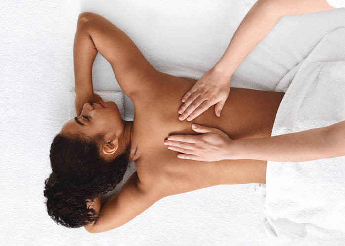 Tranquil african girl getting back massage, white background