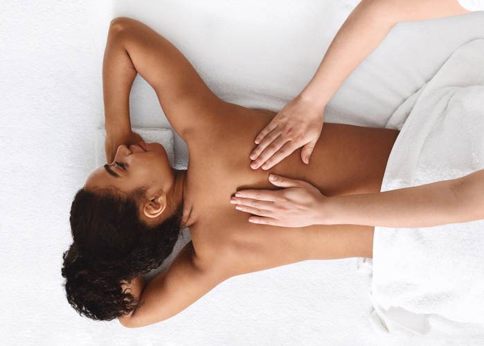 Tranquil african girl getting back massage, white background Tranquil african girl getting back massage, white background