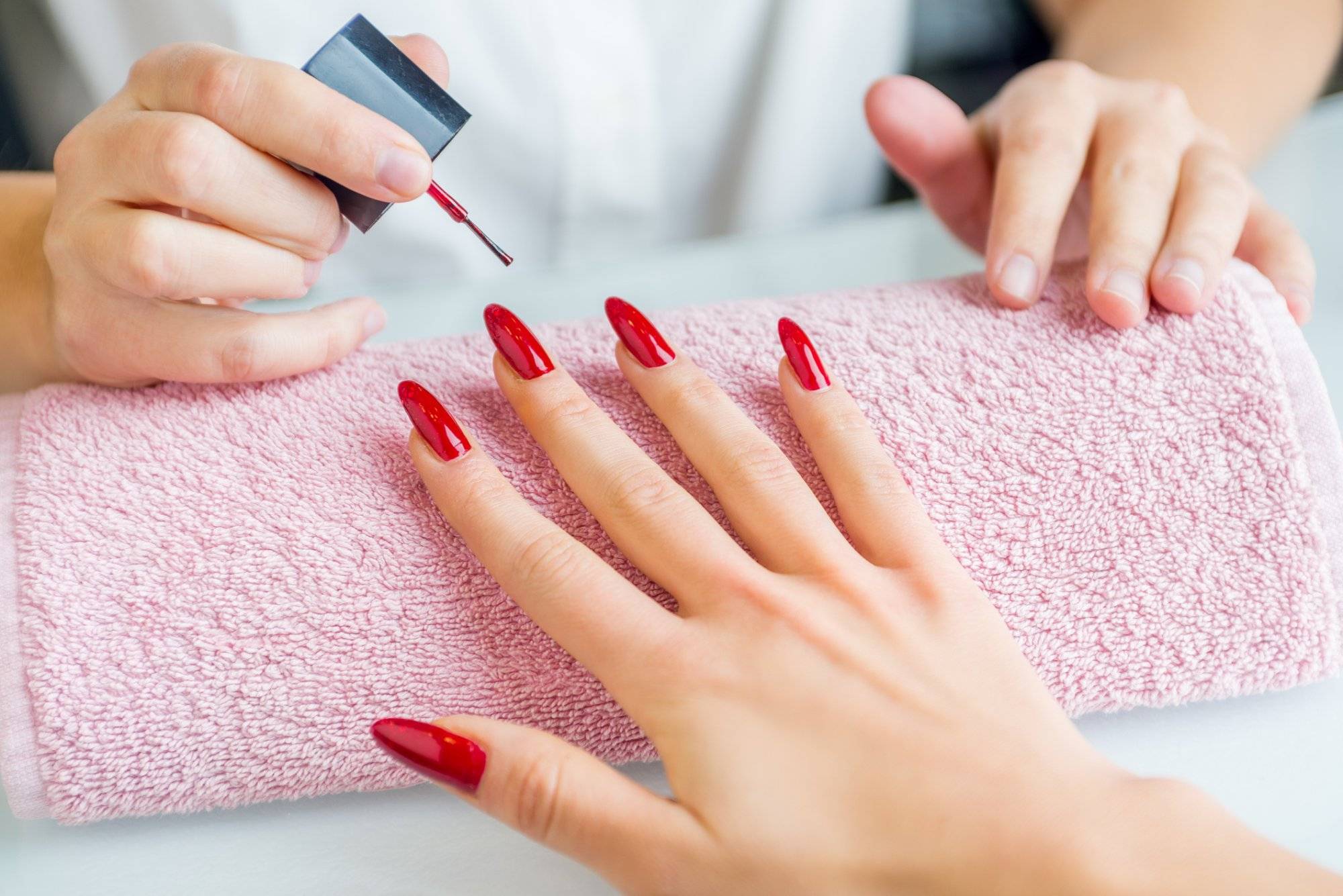 A woman with red painted nails getting a manicure A woman with red painted nails getting a manicure