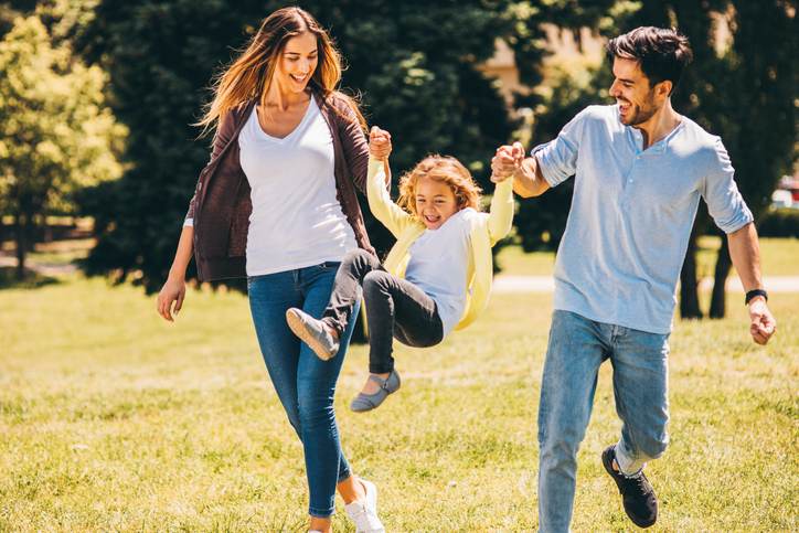 Parents swinging their daughter in the air